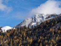 Über dem Herbstwald im Priental sind die Gipfel frisch verschneit